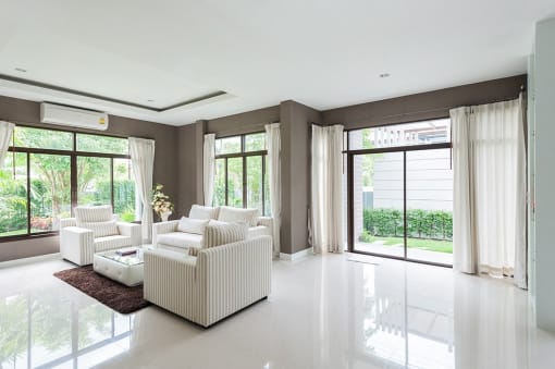 a living room with white furniture and large windows