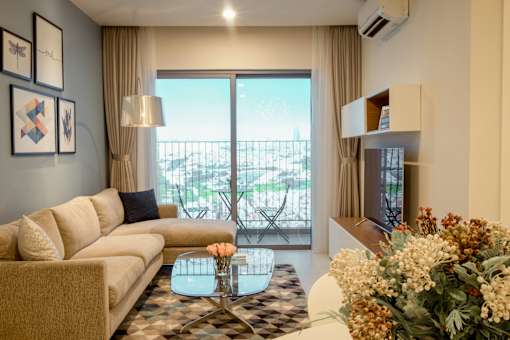 A living room with a couch, coffee table, and a view of the balcony.