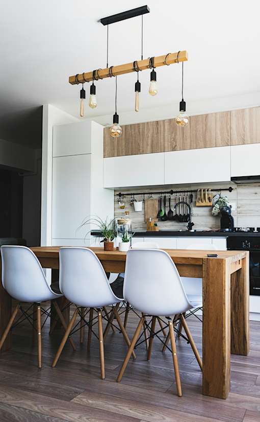 A modern kitchen with a wooden table and white chairs.
