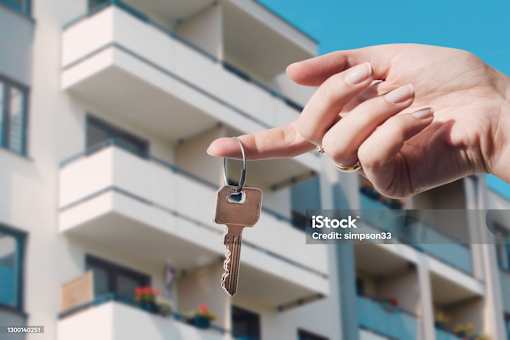 A hand holding a key in front of a building.
