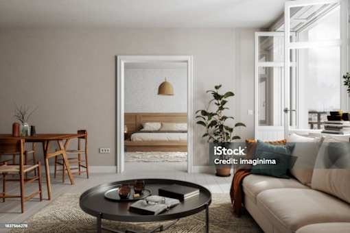 A modern living room with a dining area and a bedroom in the background.