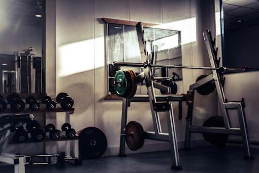 A gym with a weight bench, dumbbells, and a barbell.