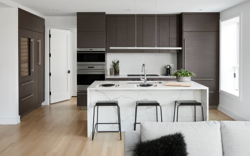 a white kitchen with black cabinets and a white island with three stools