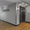 A hallway with a wooden floor and a white wall with the word MIRADA on it.