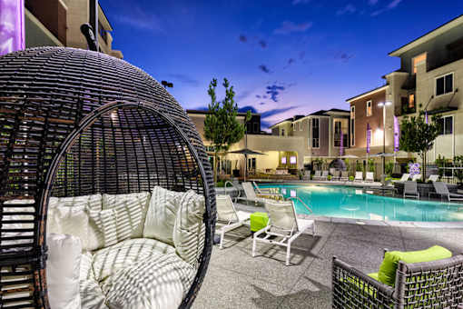a patio with a pool and chairs at night