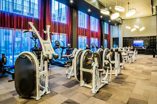 a gym with cardio machines and a television