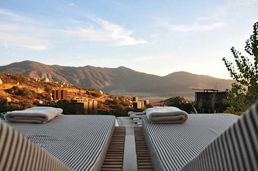 A mountain range is in the background of a building with a striped roof.