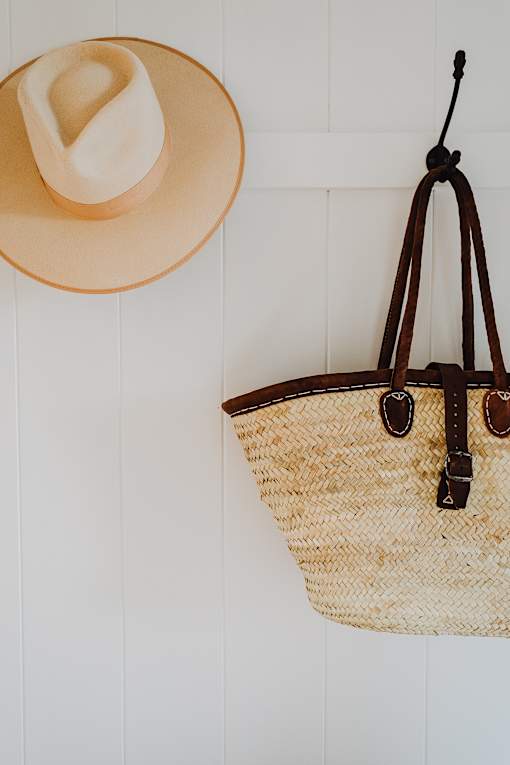 a hat and a straw bag hanging on a wall