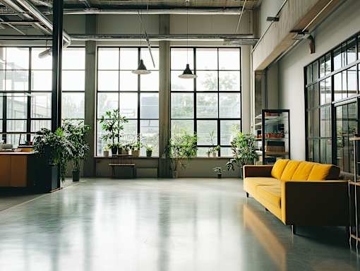 A brightly lit room with a yellow couch and large windows.