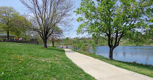 people walking along a path next to a lake