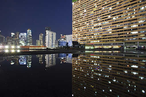 a city skyline at night reflected in the water of a river