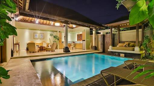 the pool and living area of a villa at night