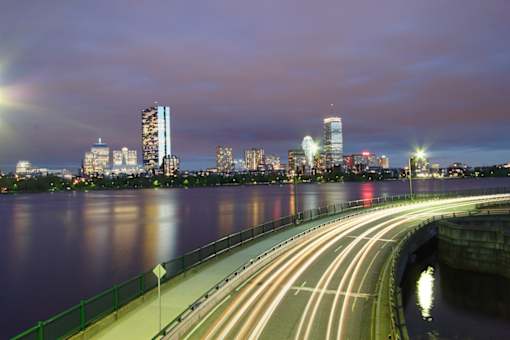 A long exposure shot of a bridge over a body of water with a city skyline in the background.