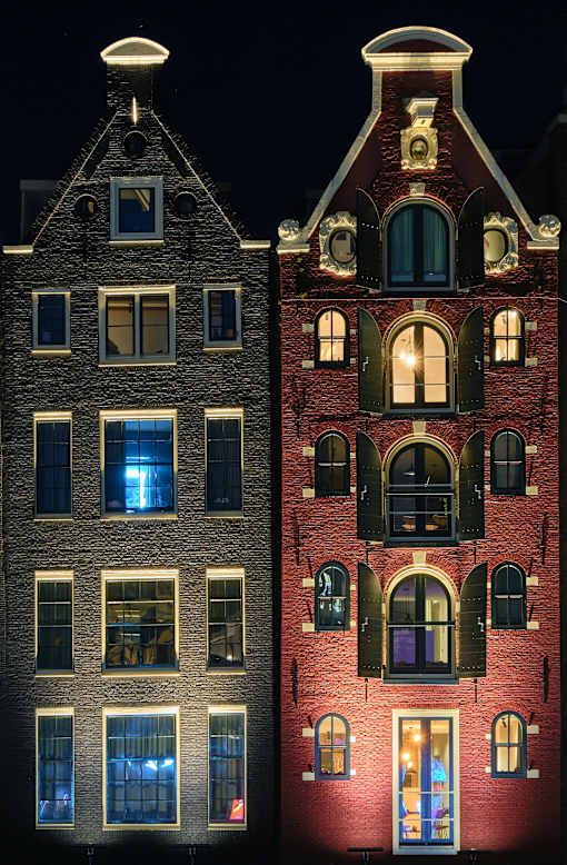 Two buildings with lit windows at night.