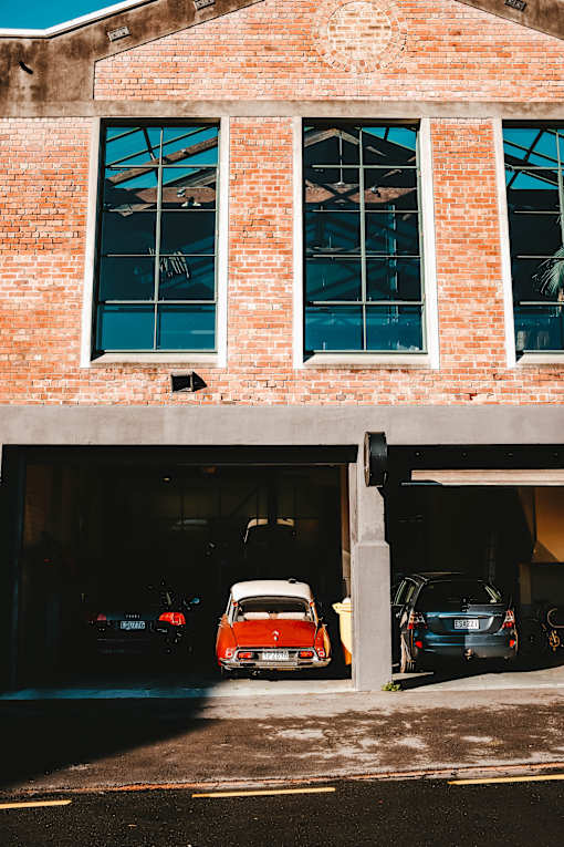 a red car parked in a parking lot in front of a brick building