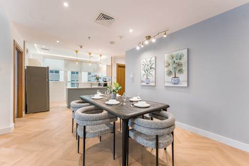 A dining room with a table set for two and a view of a kitchen.