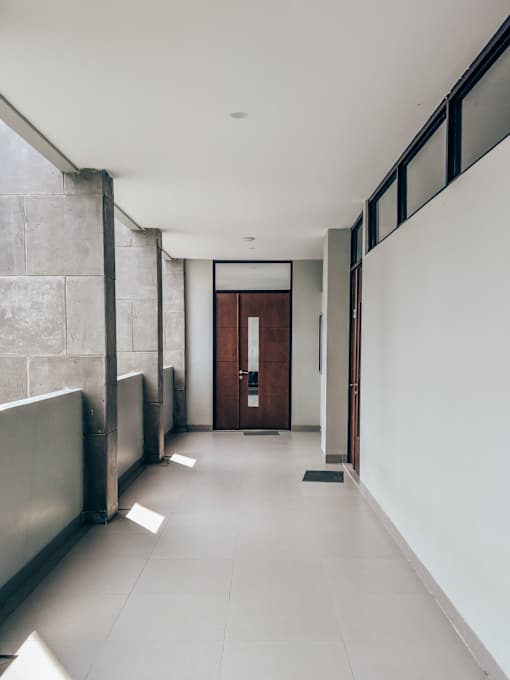 A long hallway with a brown door at the end.