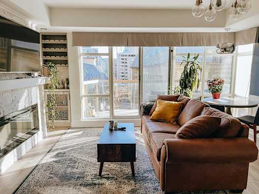 A living room with a brown leather couch and a fireplace.