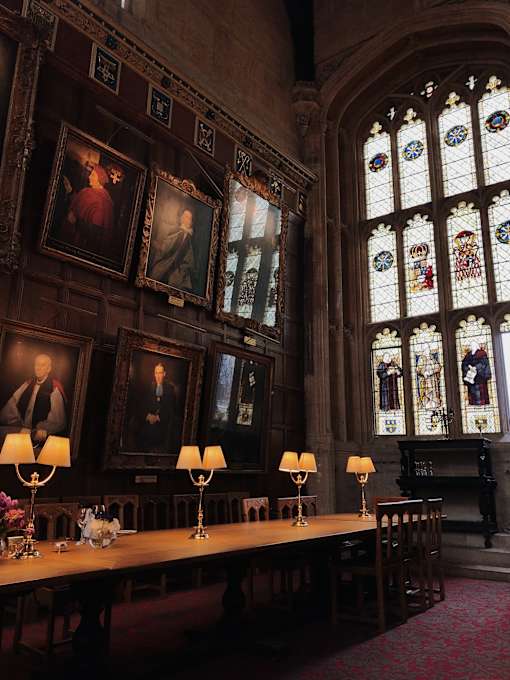 a room with a long table with lamps on it and a stained glass window in the background