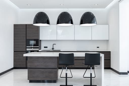 A modern kitchen with a white countertop and black chairs.
