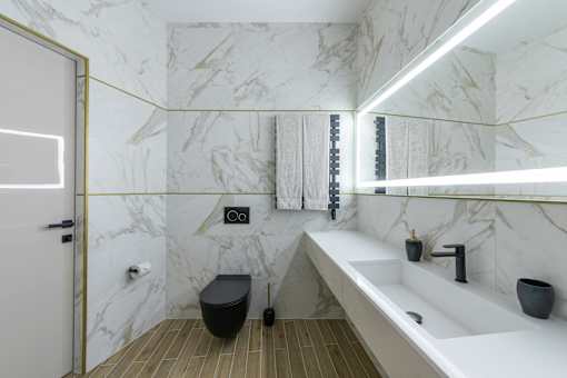 A bathroom with a marble wall and a white sink.