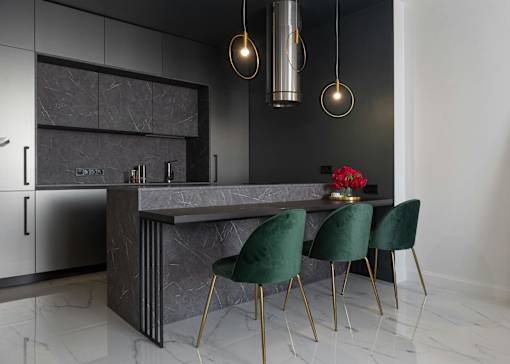A modern kitchen with a dark grey countertop and green chairs.