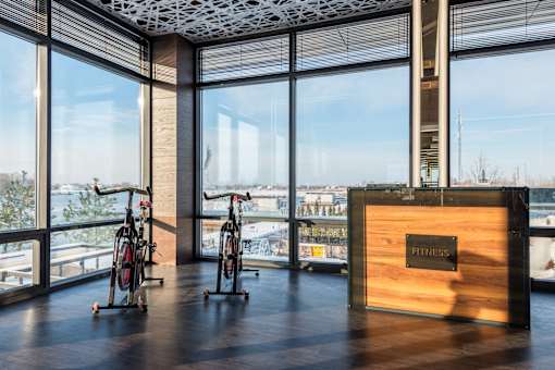 Two bikes are parked in front of a large window with a view of the water.