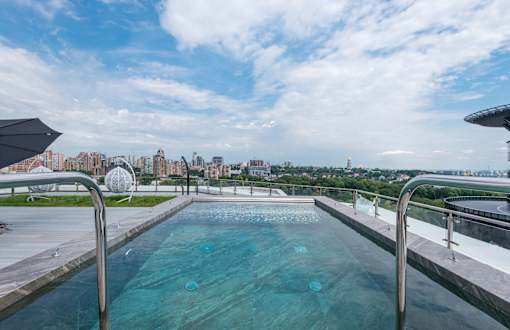 A swimming pool with a metal railing and a cityscape in the background.
