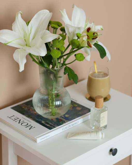 a vase with white flowers on a table with a book
