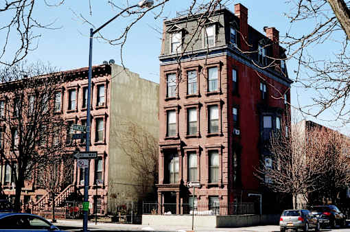 A tall red brick building with a brown brick building behind it.