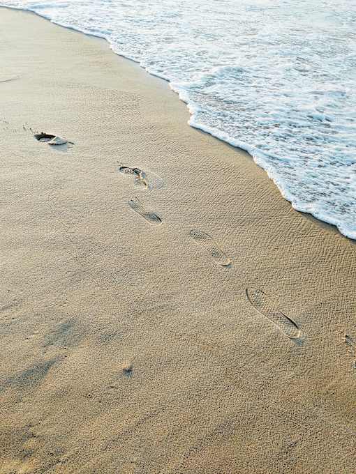Footprints in the sand leading to the water.