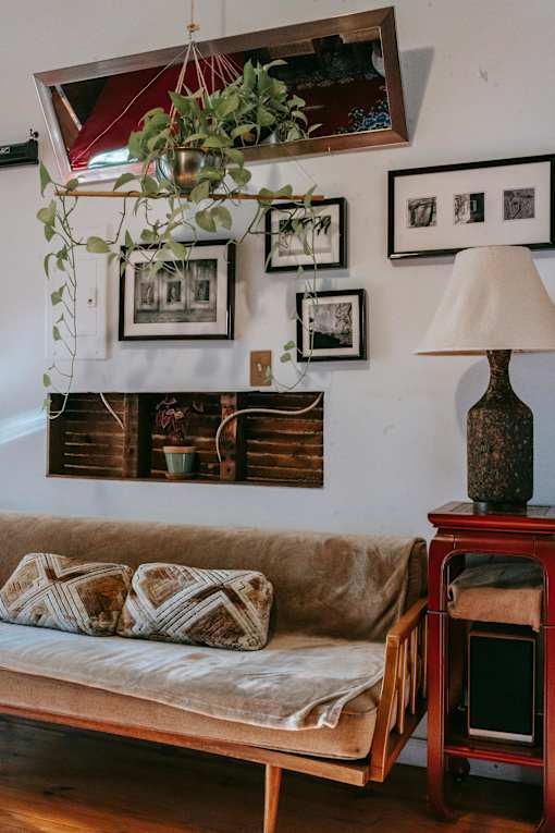 A living room with a couch, a table with a lamp, and pictures on the wall.