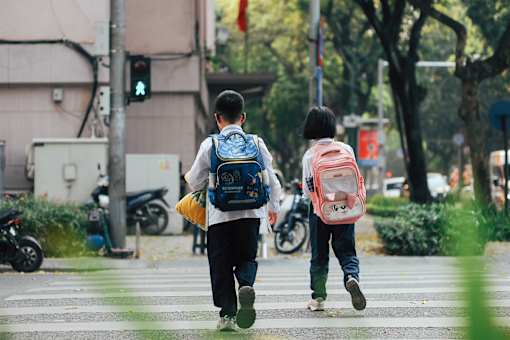 Two children with backpacks crossing the street.