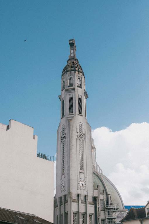 A tall white building with a clock tower is under a blue sky.