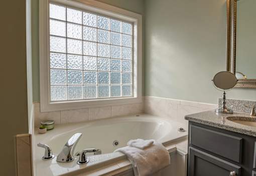 A bathroom with a tub, sink, and a window.