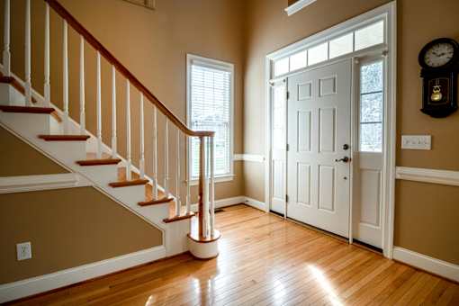 A hallway with a staircase and a white door.