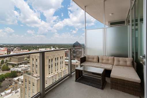A balcony with a couch and a table overlooking a cityscape.