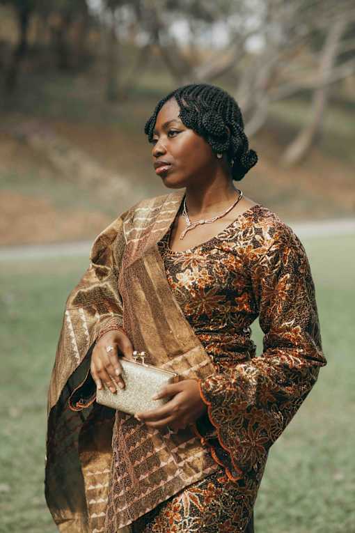 a woman in a brown dress standing in a field
