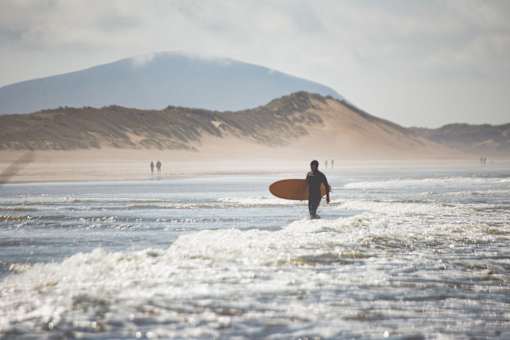 A person with a surfboard is walking into the ocean.