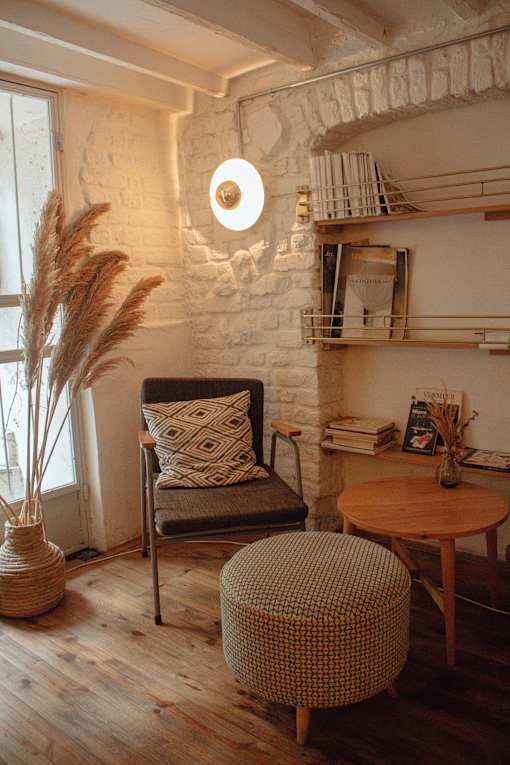 white exposed brick wall with bookshelf, chair, ottoman