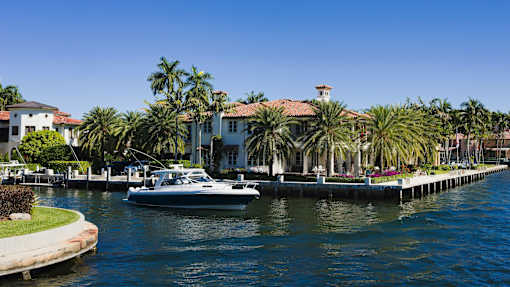 A boat is docked in front of a house with a dock.