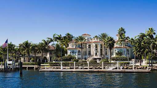 A row of houses with palm trees in front of them.