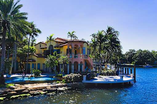 A yellow house with a pool in front of it.