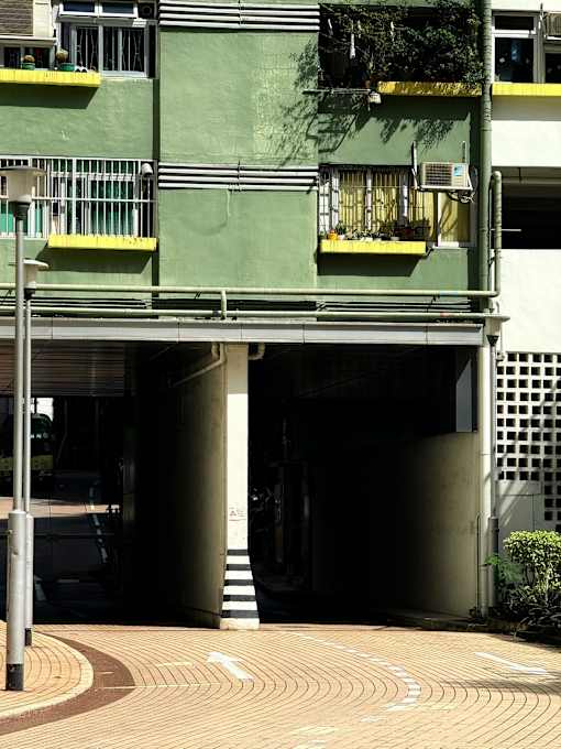A building with a green and white exterior has a balcony with plants on it.