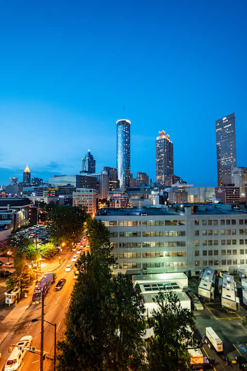 A cityscape at dusk with buildings and cars.