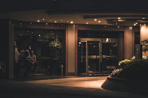 A couple is sitting on a bench outside a building at night.