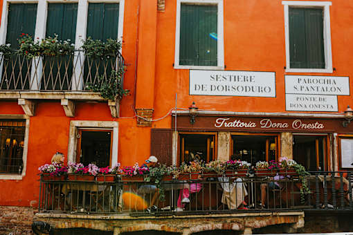 A bright orange building with a balcony full of flowers.