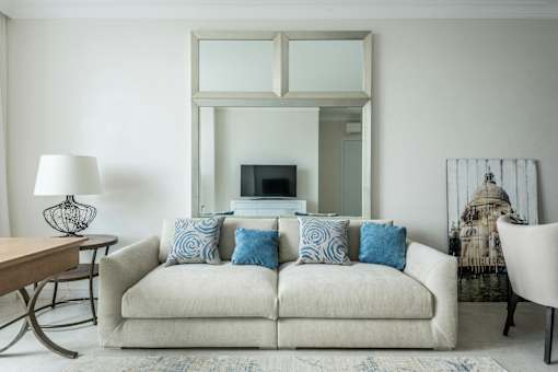 A living room with a white couch and a large mirror above it.