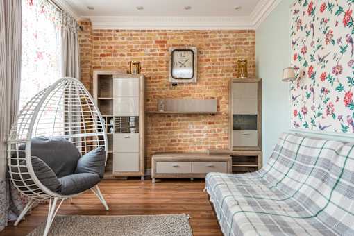 A room with a plaid couch and a hanging egg chair.