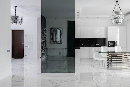 a black and white kitchen and dining room with white marble flooring and white cabinets